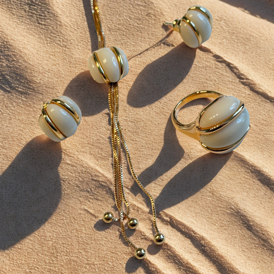 Jewelry set with necklace, ring, and earrings on a beige surface