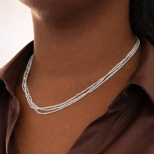 Silver necklace worn by a person with a brown shirt