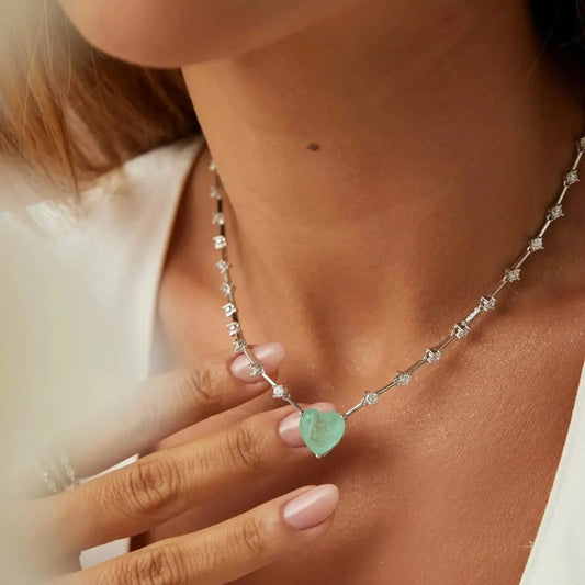 Close-up of a necklace with a green gemstone worn by a person.