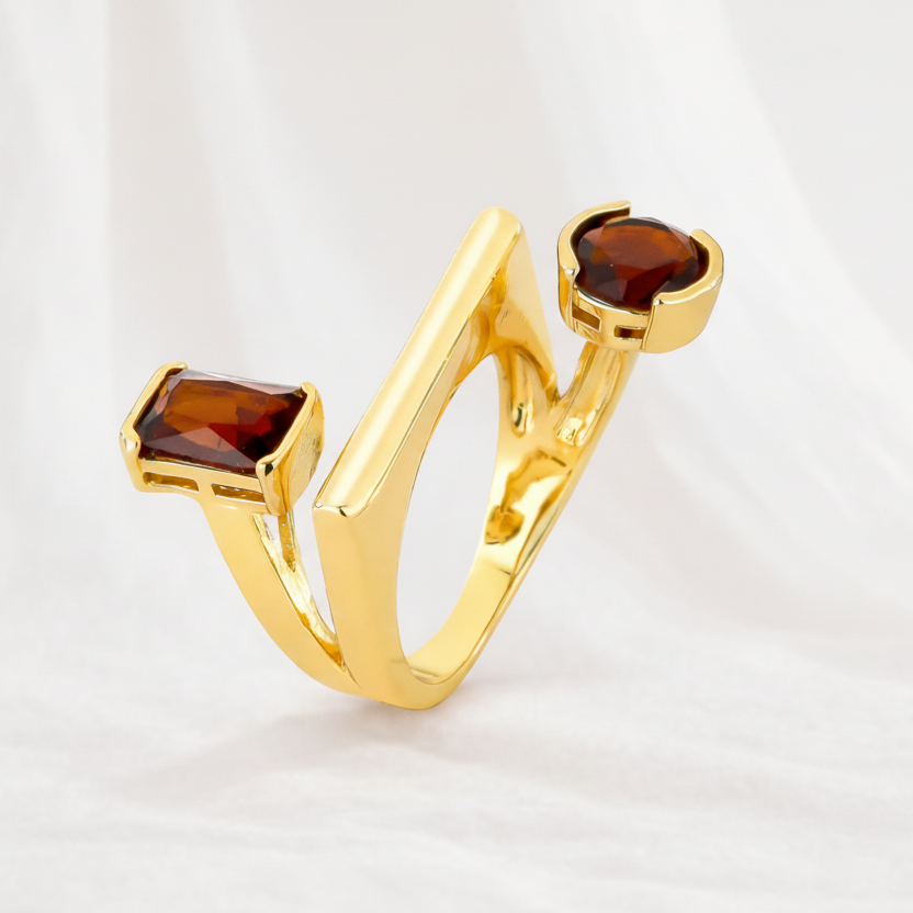 Gold ring with two brown gemstones on a light gray background