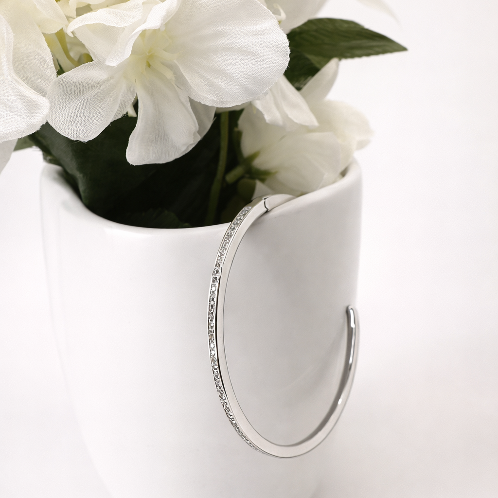White pitcher with decorative handle holding white flowers on a light background