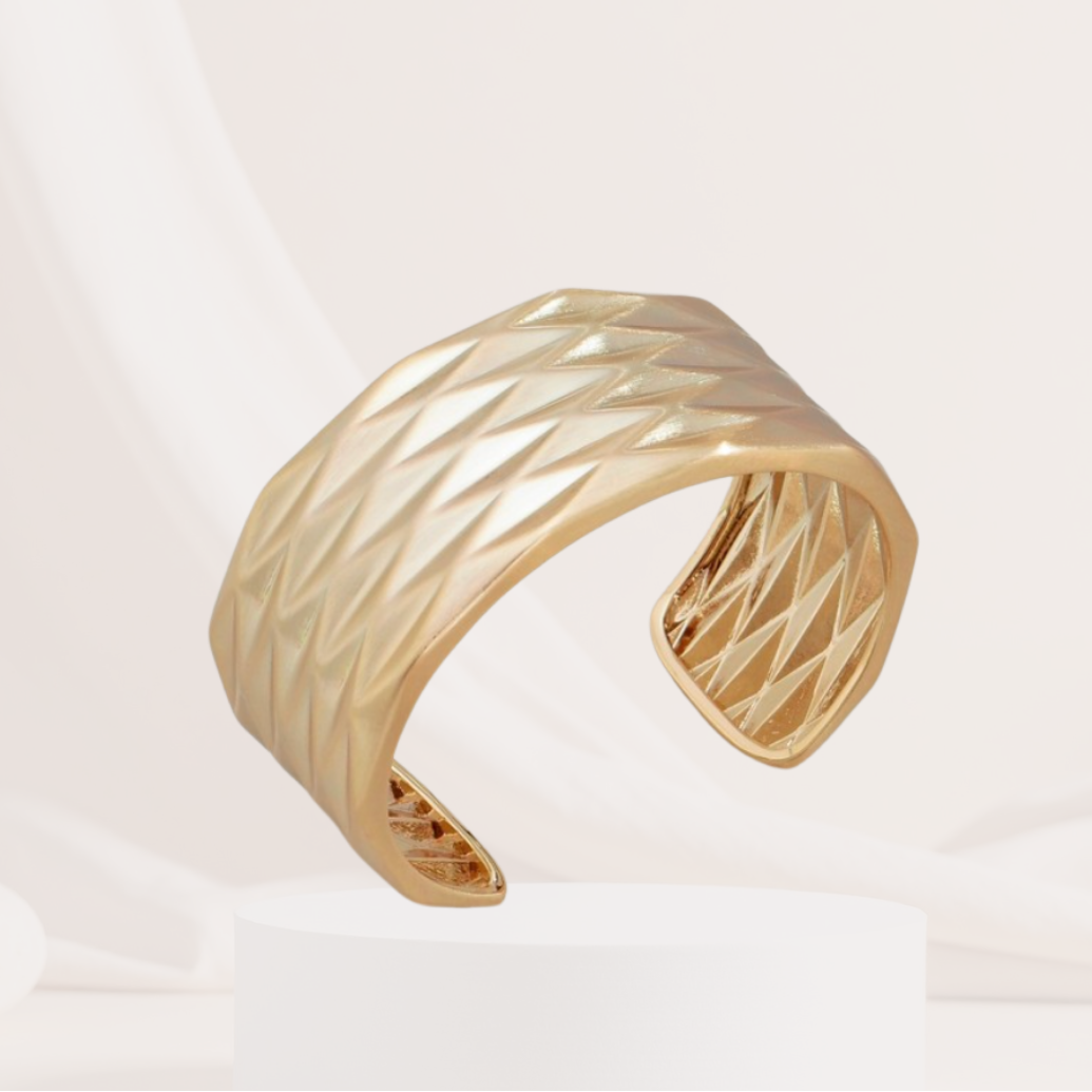Gold bracelet with a textured design on a light background
