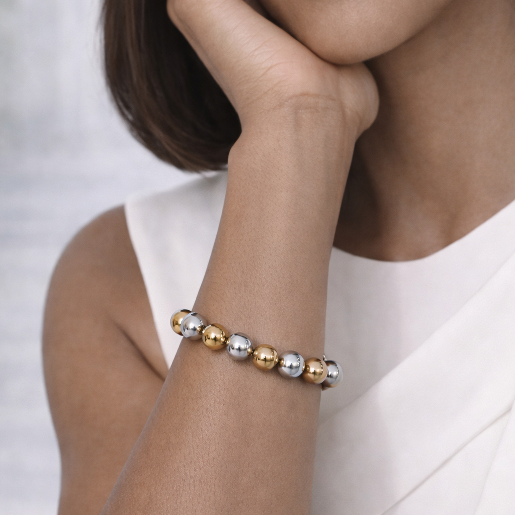 Woman wearing a bracelet with gold and silver beads on a white background