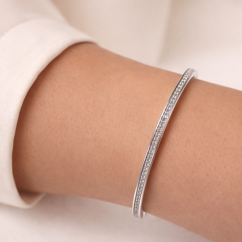 Silver bracelet on a person's wrist with a plain background