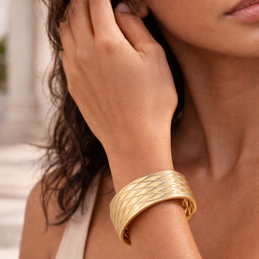 Woman wearing a gold bracelet on her wrist with a blurred background