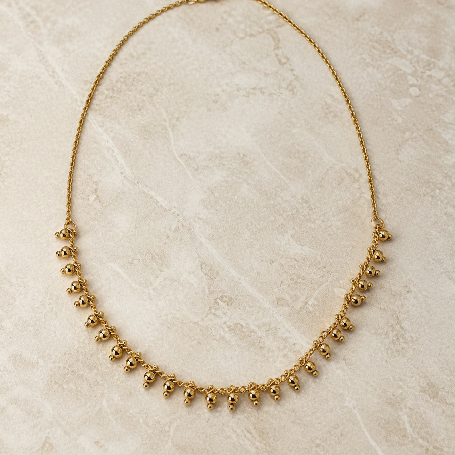 Gold necklace on a beige marble surface