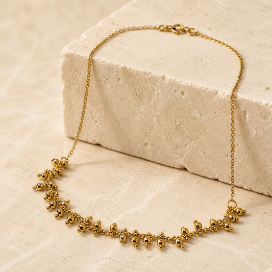 Gold necklace on a textured beige surface