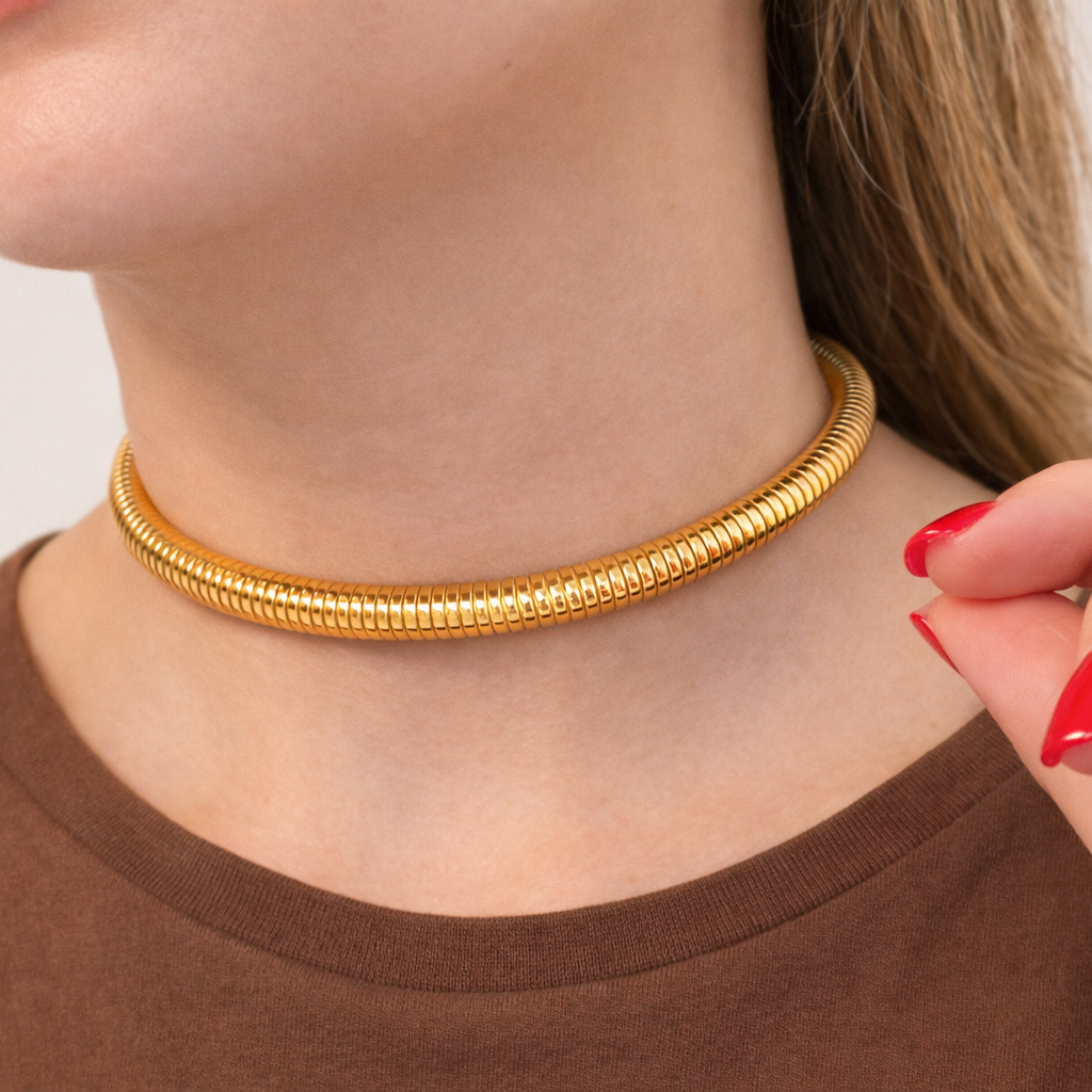 Gold choker necklace worn by a person with a neutral background