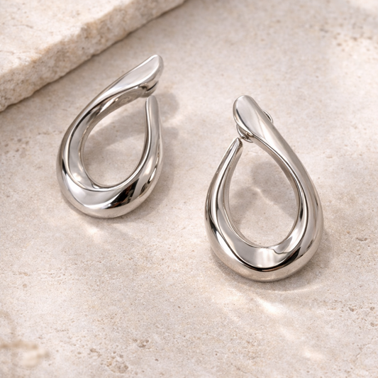 Silver teardrop earrings on a light stone surface