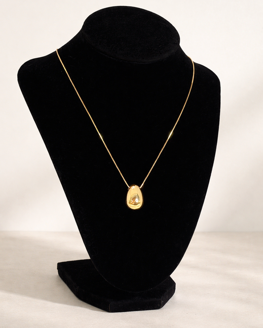 Gold necklace on a black velvet bust against a white background