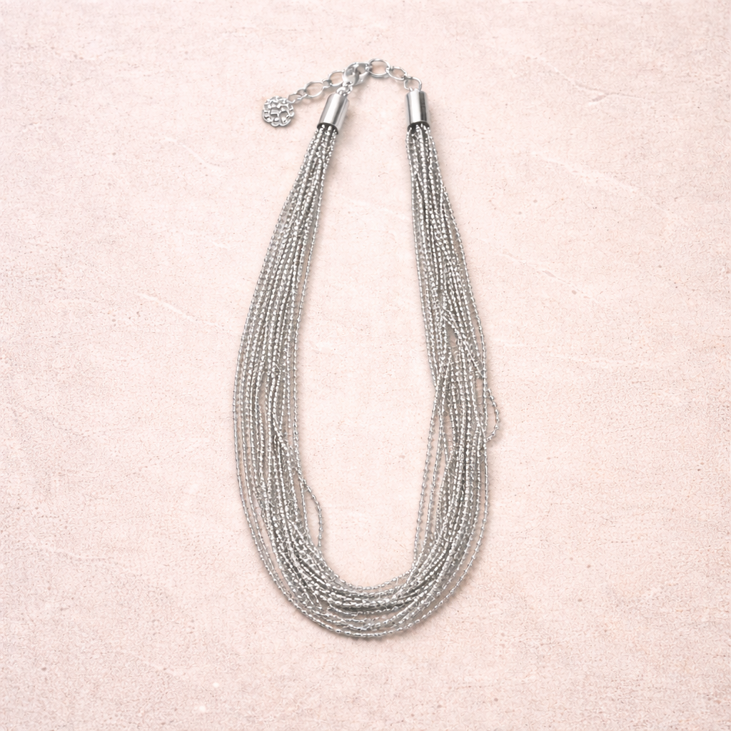 Multi-strand silver necklace on a light pink background
