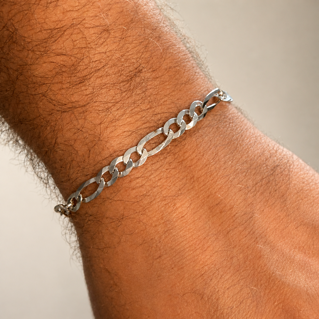 Silver chain bracelet on a wrist with a neutral background