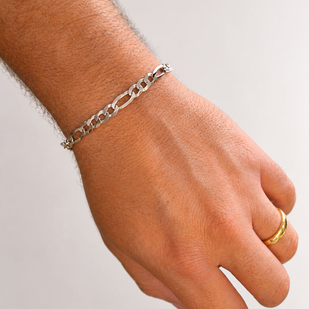Hand wearing a silver chain bracelet on a light background