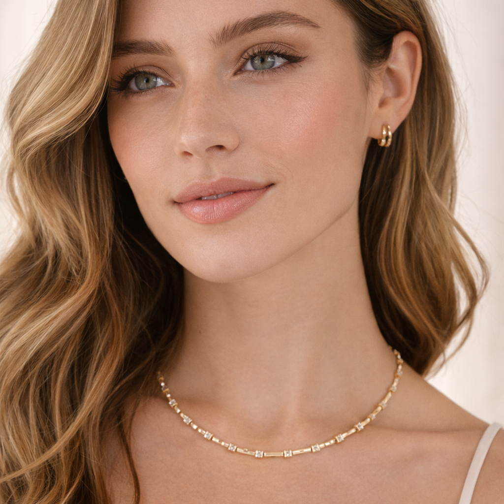 Woman wearing a gold necklace and earrings against a neutral background