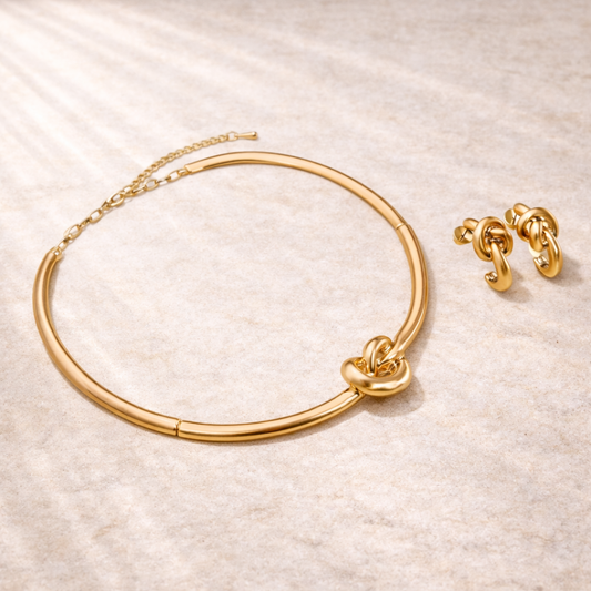 Gold necklace 
and earrings on a textured beige surface