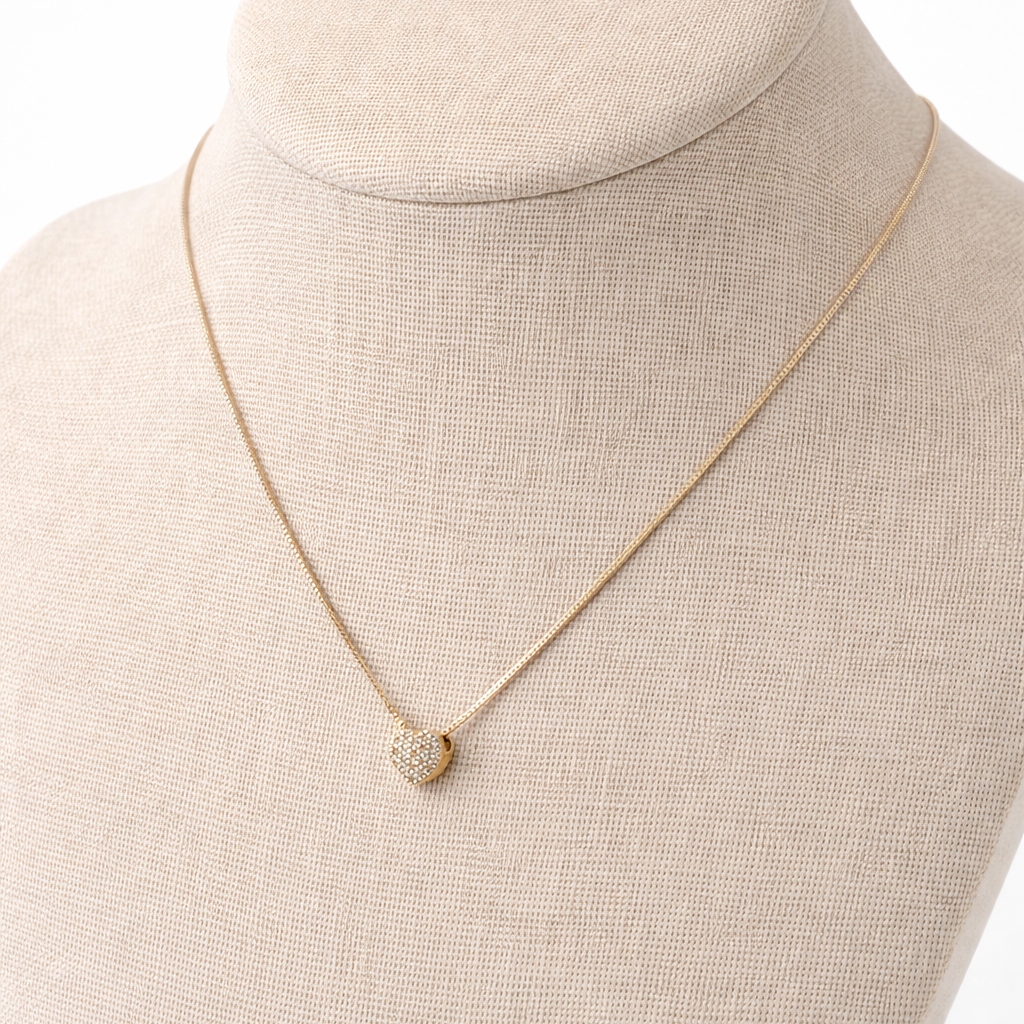 Gold necklace with a heart pendant on a beige mannequin bust against a white background