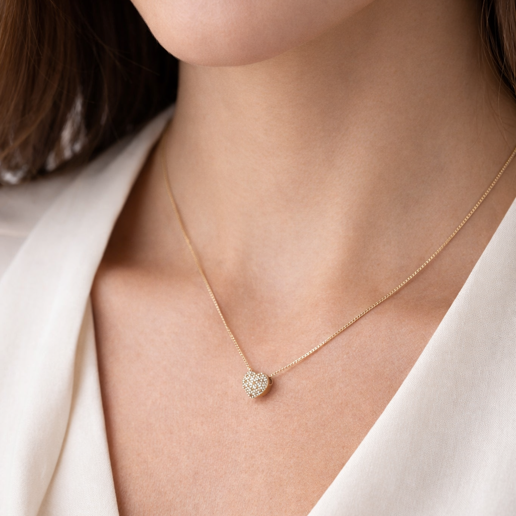 Necklace with a heart-shaped pendant worn by a person in a white outfit.