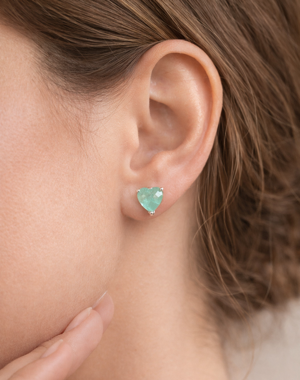 Close-up of a person wearing a heart-shaped turquoise earring.