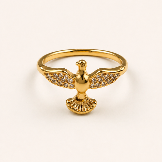 Gold ring with a dove design on a light beige background