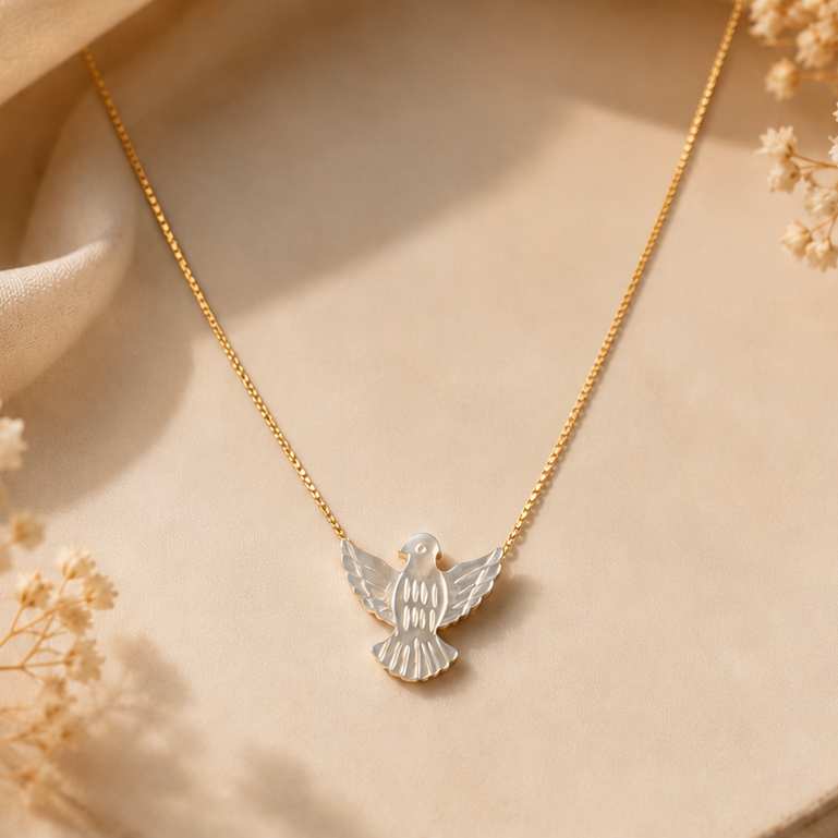 Gold necklace with a dove pendant on a beige fabric background