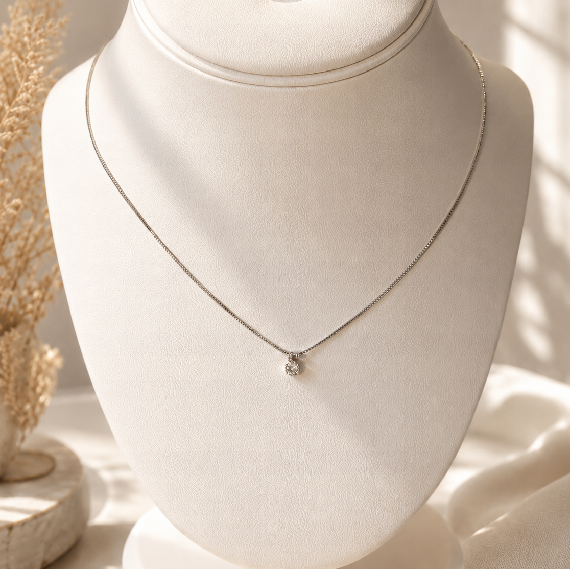 Silver necklace on a mannequin bust with a soft, warm background