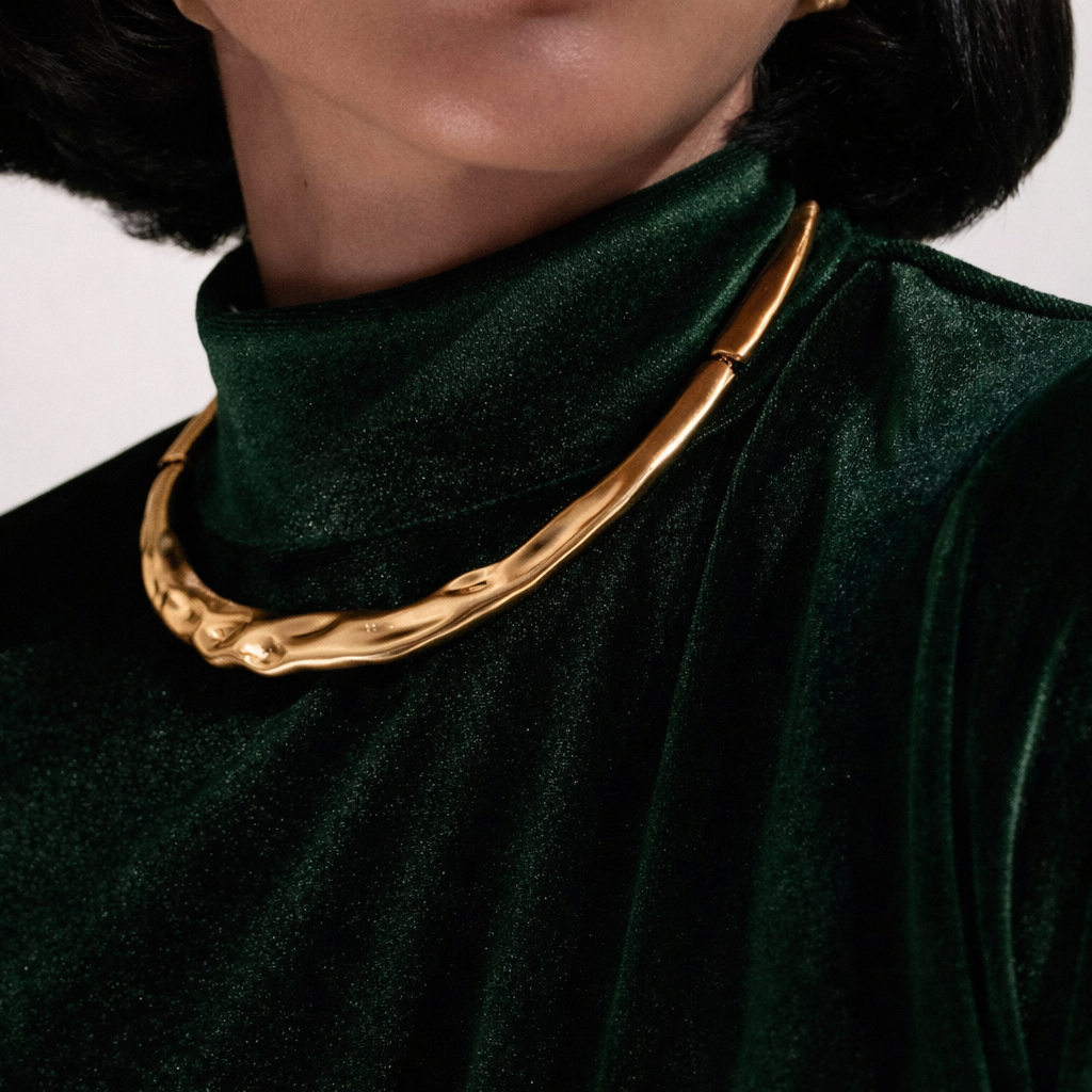 Gold necklace on a person wearing a dark green outfit