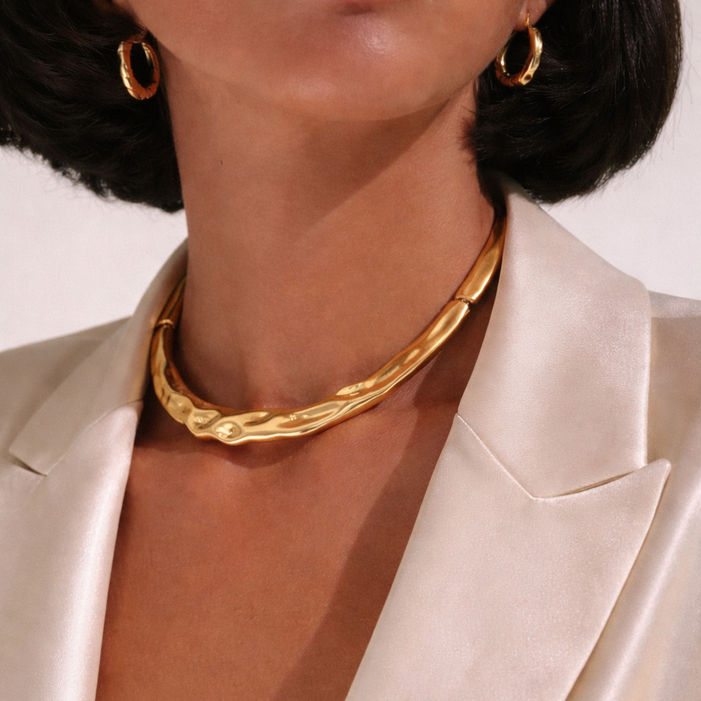 Close-up of a person wearing a gold necklace and earrings with a white satin garment.