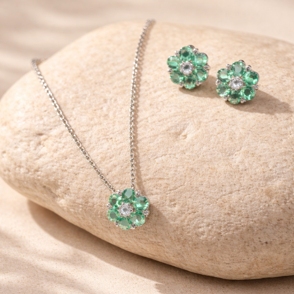 Jewelry set with green floral earrings and necklace on a beige stone