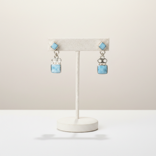 Necklace and earrings on a mannequin bust and stand against a white background