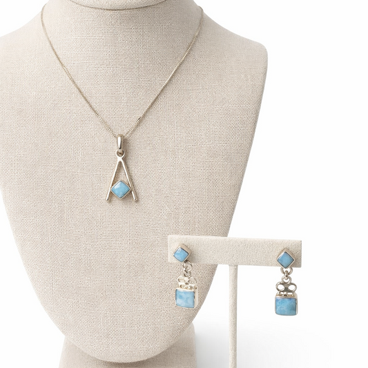 Necklace and earrings on a mannequin bust and stand against a white background