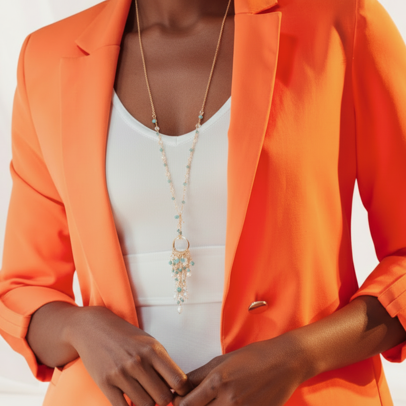 Person wearing an orange blazer over a white top with a necklace.
