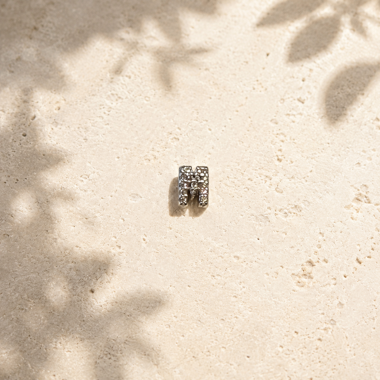 Silver ring with gemstones on a sandy surface
