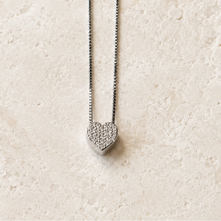 Heart-shaped pendant necklace on a light beige textured background
