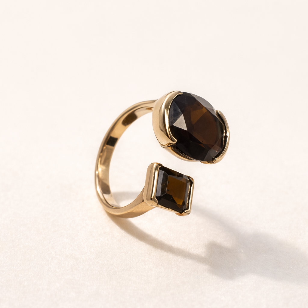 Gold ring with smoky brown gemstones on a light beige background