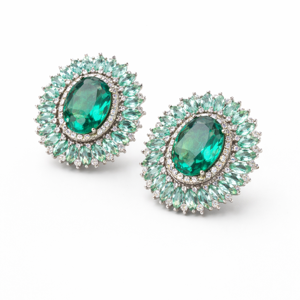 Pair of emerald green earrings with clear stones on a white background