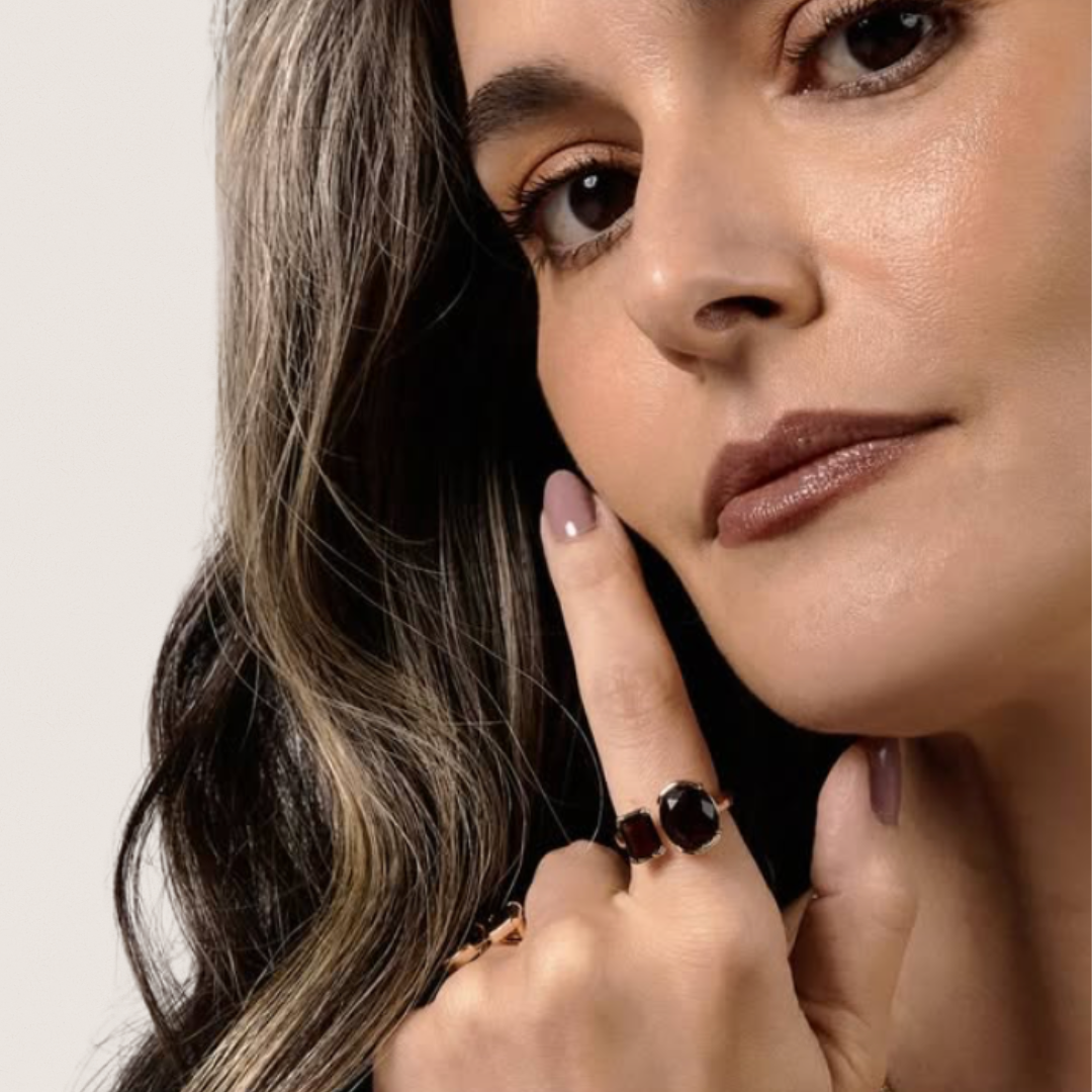 Woman wearing a brown ring on her finger, with a neutral background