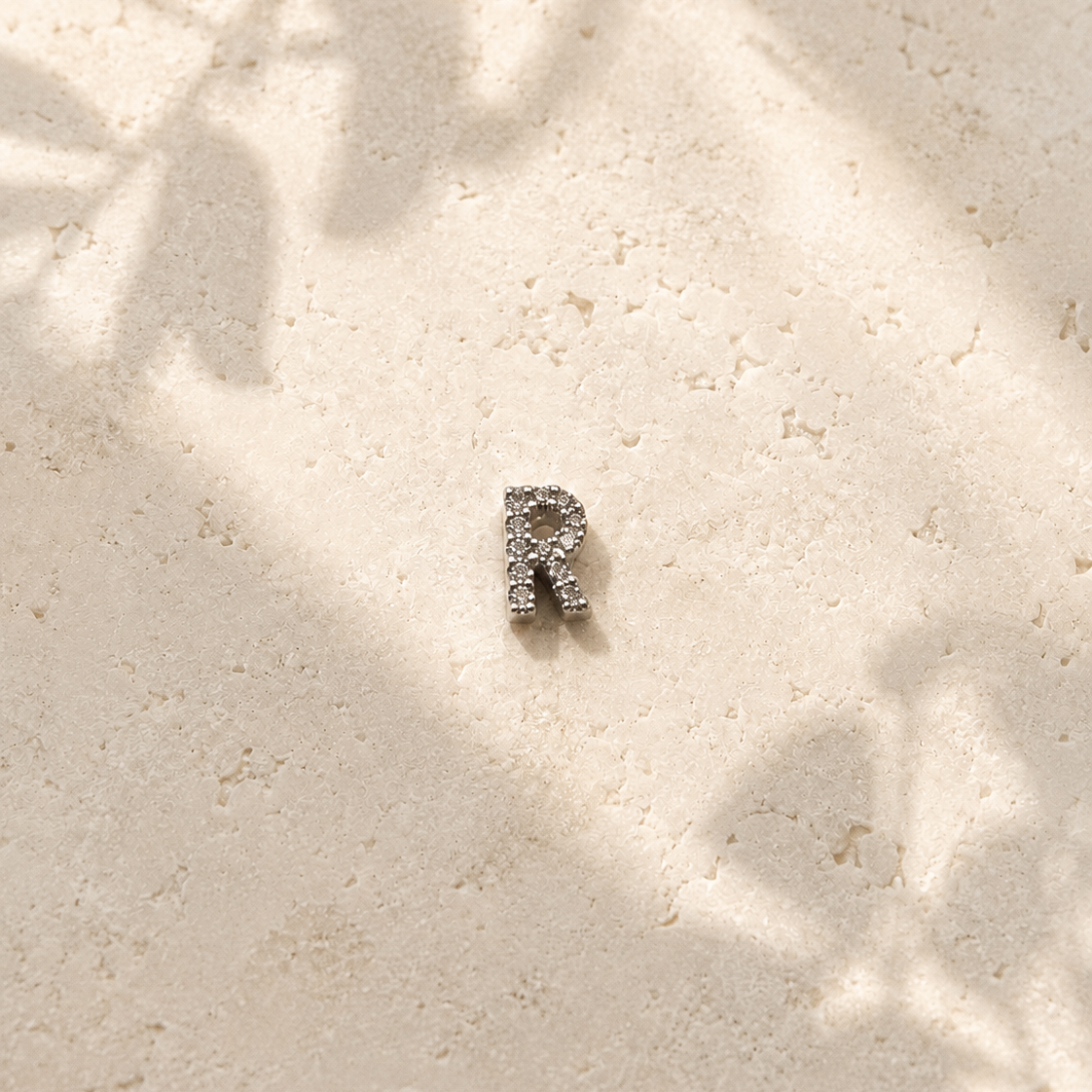 Silver pendant with a small zirconias on a textured beige surface