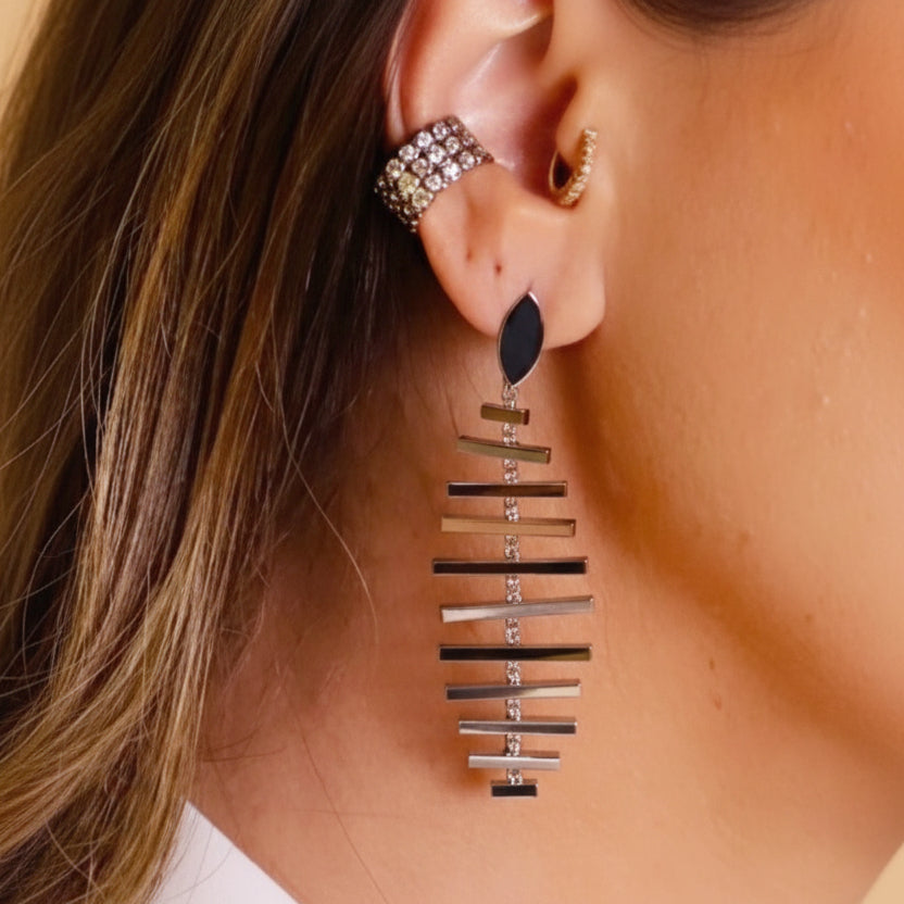 Close-up of an ear wearing long earring and  a white shirt.