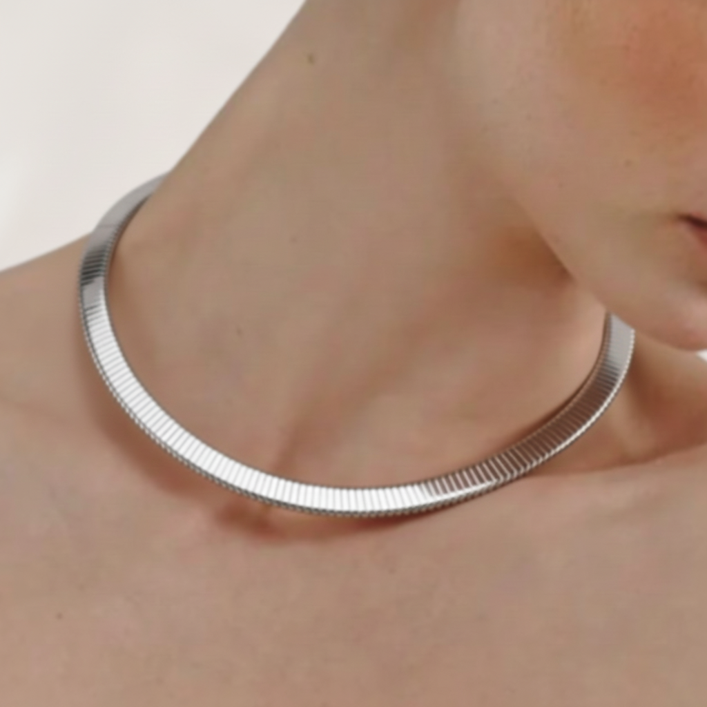 Silver choker on a person's neck against a neutral background