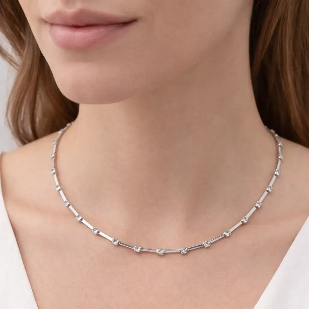 Silver necklace worn by a person against a neutral background