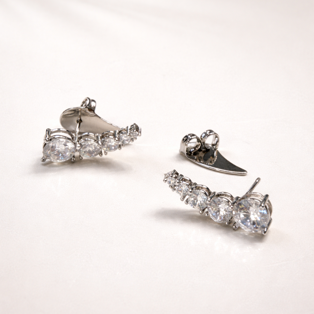 Pair of silver earrings with clear gemstones on a light pink background