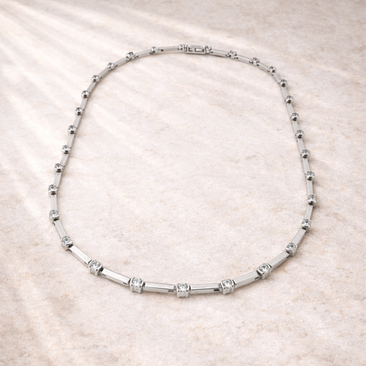 Silver necklace with small beads on a beige fabric background