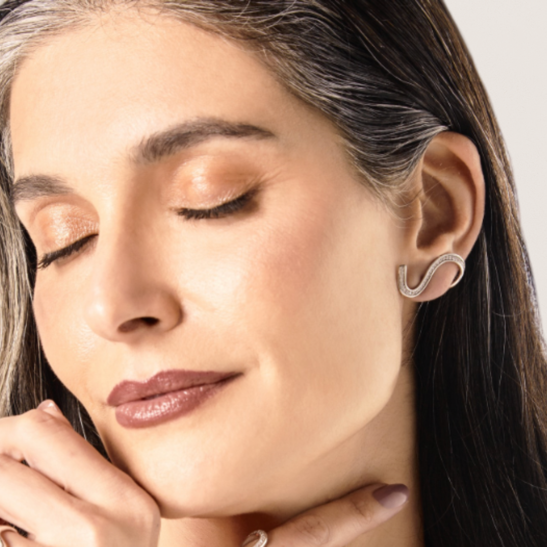 Close-up of a woman wearing a silver earring with a neutral background