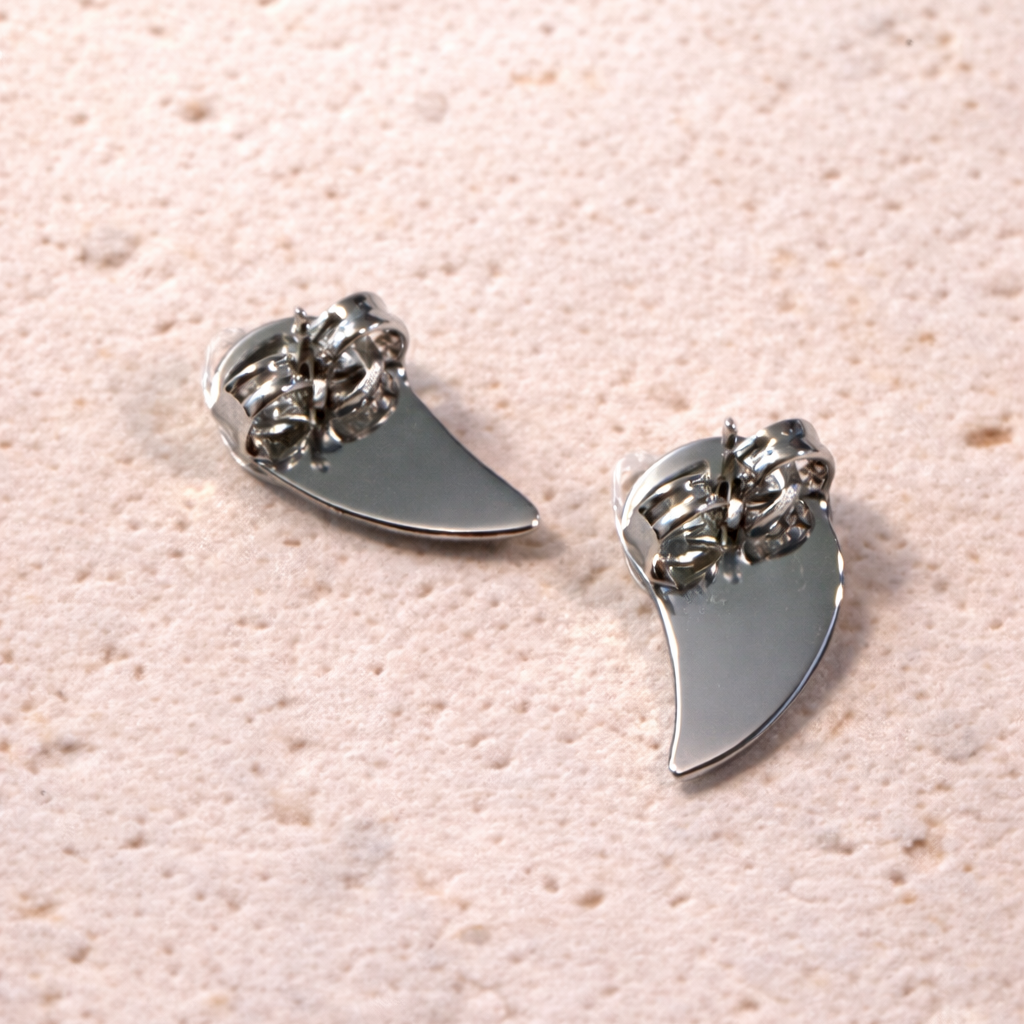 Pair of silver earrings  back on a textured pink surface