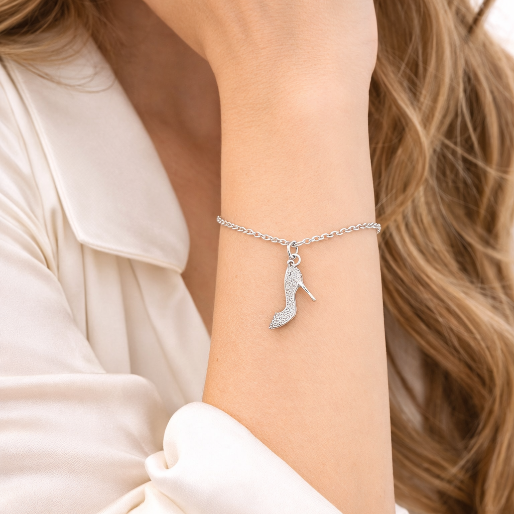 Silver bracelet with a shoe charm on a person's wrist, wearing a light-colored top.