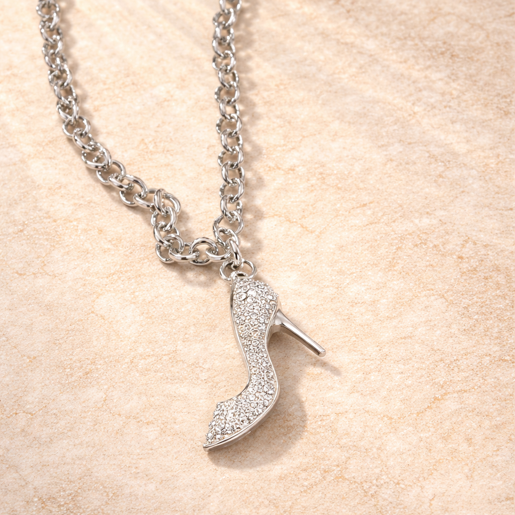 Silver high-heeled shoe pendant on a chain against a beige background