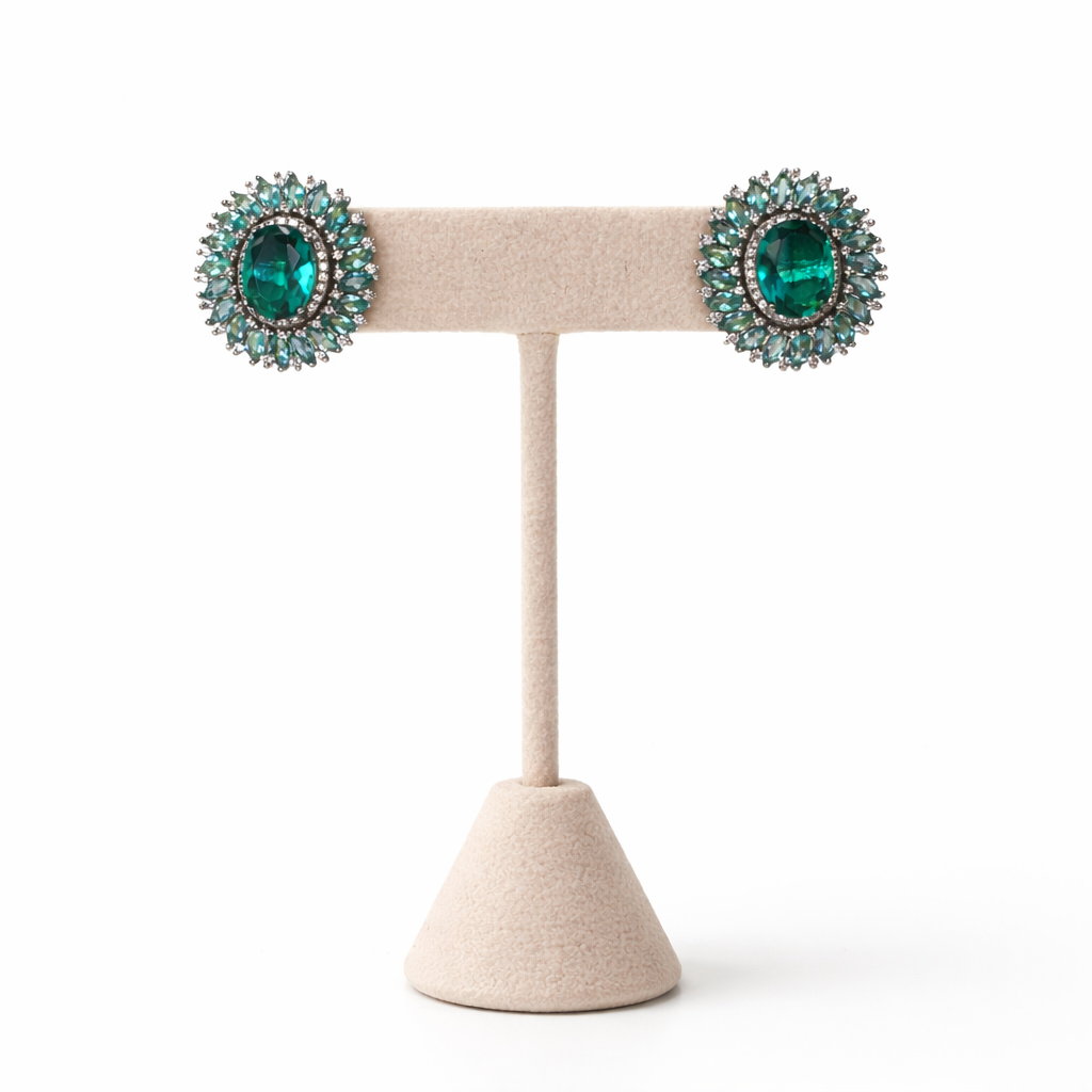 Pair of green gemstone earrings on a beige stand against a white background