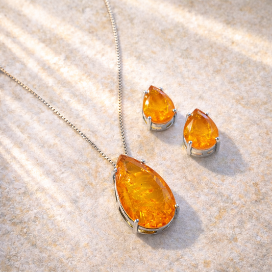 Amber teardrop necklace and earrings on a textured beige surface