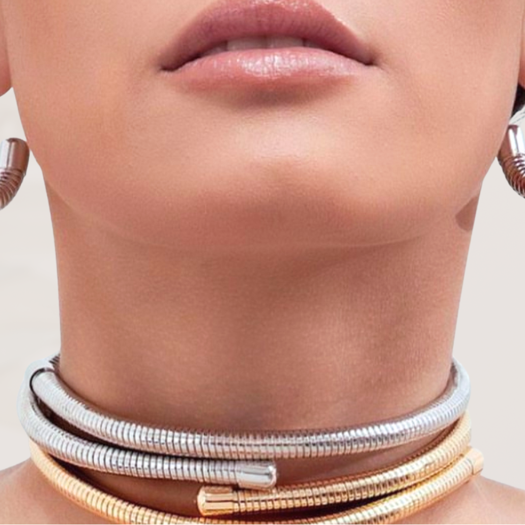 Close-up of a person wearing multiple necklaces with a neutral background