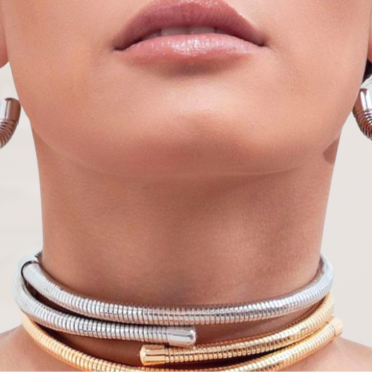 Close-up of a person wearing multiple necklaces with a neutral background